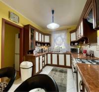 VKUSNÝ 4-IZBOVÝ RODINNÝ DOM S GARÁŽOU NA PREDAJ V OBCI TOPOĽNÍKY - Kuchyňa v rodinnom dome s dreveným dekorom, žlté steny, biely spotrebič.