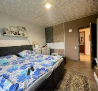 VKUSNÝ 4-IZBOVÝ RODINNÝ DOM S GARÁŽOU NA PREDAJ V OBCI TOPOĽNÍKY - Spálňa v rodinnom dome s posteľou, podlahou s dreveným dekorom a kvetinovým obliečkami.