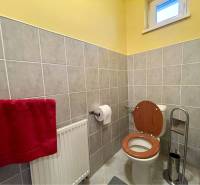 VKUSNÝ 4-IZBOVÝ RODINNÝ DOM S GARÁŽOU NA PREDAJ V OBCI TOPOĽNÍKY - Kúpeľňa v rodinnom dome s toaletou, červeným uterákom a kachličkovými stenami.