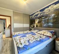 VKUSNÝ 4-IZBOVÝ RODINNÝ DOM S GARÁŽOU NA PREDAJ V OBCI TOPOĽNÍKY - Spálňa v rodinnom dome s tapetou vodopádu a posteľou s kvetinovou posteľnou bielizňou.