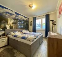 VKUSNÝ 4-IZBOVÝ RODINNÝ DOM S GARÁŽOU NA PREDAJ V OBCI TOPOĽNÍKY - Spálňa v rodinnom dome s posteľou a nástennou dekoráciou, podlaha s dreveným dekorom.