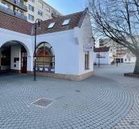 DUNASJKÁ STREDA – OBCHODNÁ BUDOVA PRIAMO V CENTRE MESTA - Exteriér obchodných priestorov na Námestí Ármina Vámbéryho v Dunajskej Strede s dlažbou a stromom.