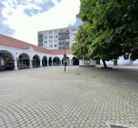 Obchodný priestor na prenájom v srdci Dunajskej Stredy - Obchodné priestory na Námestí Ármina Vámbéryho v Dunajskej Strede, obkolesené stromami a oblúkmi.