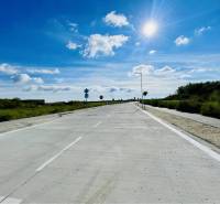 DUNAJSKÁ STREDA – SLNEČNÉ STAVEBNÉ POZEMKY NA PREDAJ V PROJEKTE VINICA - Slnečný deň na ceste v Dunajskej Strede, obklopená zeleňou, pozemky - bývanie.