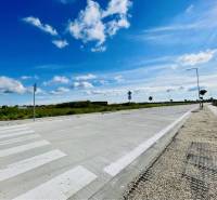 DUNAJSKÁ STREDA – SLNEČNÉ STAVEBNÉ POZEMKY NA PREDAJ V PROJEKTE VINICA - Cesta a chodník v Dunajskej Strede, pozemky - bývanie, neuvedená ulica pod modrou oblohou.