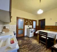 TOPOĽNÍKY – 4-IZBOVÝ RODINNÝ DOM NA PREDAJ NA 14 ÁROVOM POZEMKU - Kuchyňa v rodinnom dome s podlahou s dreveným dekorom, jedálenským stolom a plynovým sporákom.