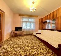 TOPOĽNÍKY – 4-IZBOVÝ RODINNÝ DOM NA PREDAJ NA 14 ÁROVOM POZEMKU - Obývacia izba v rodinnom dome s kobercom kvetinového vzoru a drevenou obývacou stenou.