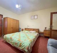 TOPOĽNÍKY – 4-IZBOVÝ RODINNÝ DOM NA PREDAJ NA 14 ÁROVOM POZEMKU - Spálňa v rodinnom dome s posteľou, skriňou, stolíkom a červeným kobercom.