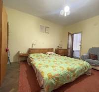 TOPOĽNÍKY – 4-IZBOVÝ RODINNÝ DOM NA PREDAJ NA 14 ÁROVOM POZEMKU - Spálňa v rodinnom dome s posteľou, skrinkami, kreslom a prístupom do kúpeľne.