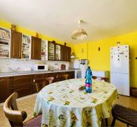 A-W REAL | POSCHODOVÝ DVOJDOM S GARÁŽOU NA PREDAJ V OBCI BÚČ - Kuchyňa v rodinnom dome s okrúhlym stolom, žltými stenami a dreveným nábytkom.