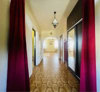 A-W REAL | POSCHODOVÝ DVOJDOM S GARÁŽOU NA PREDAJ V OBCI BÚČ - Chodba s podlahou s dreveným dekorom, červenými závesmi a lustrom v rodinnom dome.