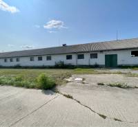 Kostolné Kračany - skladové - prevádzkové priestory na predaj za cenu  - Výrobné priestory na Amadeho Kračany v Kostolných Kračanoch, nízka budova s betónovou plochou.