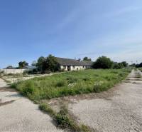 Kostolné Kračany - skladové - prevádzkové priestory na predaj za cenu  - Výrobné priestory na ulici Amadeho Kračany, Kostolné Kračany, so zeleňou a budovou v pozadí.