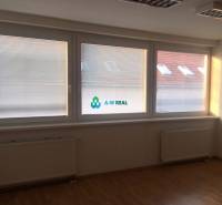 Kancelárie v centre mesta. - Priestranná kancelária s drevenou podlahou a veľkými oknami, nachádzajúca sa na ulici Hlavná.