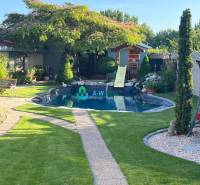 Znížená cena!  Rodinný dom s vnútorným aj vonkajším bazénom na krásne  - Rodinný dom s trávnikom, bazén so šmykľavkou, strom, chodník, plot.