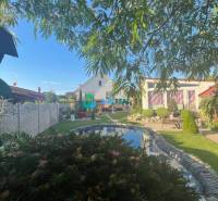 Znížená cena!  Rodinný dom s vnútorným aj vonkajším bazénom na krásne  - Záhrada rodinného domu s jazierkom na ulici neuvedene, obklopená zeleňou a kvetmi.