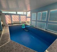 Znížená cena!  Rodinný dom s vnútorným aj vonkajším bazénom na krásne  - Rodinný dom má krytý bazén s modrými stenami a veľkými oknami na ulici neuvedene.