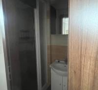 Apartmány na prenájom. - Kúpeľňa v budove s drevenými dverami, umývadlom a preskleným sprchovacím kútom.