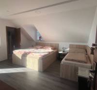 Apartmány na prenájom. - Spálňa s dvoma posteľami a oknom v podkrovnej budove.