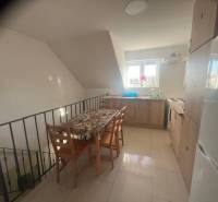 Apartmány na prenájom. - Kuchyňa s jedálenským stolom, okno a svetlé drevené skrinky, stoličky. Priestranná budova.