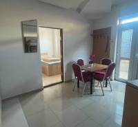 Apartmány na prenájom. - Jedáleň so stolom, stoličkami a izbou. Interiér v neutrálnej farebnosti, svetlá podlaha.