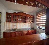 Rodinný  dom na predaj v Gabčíkove - Kuchyňa so skrinkami v rodinnom dome, drevený nábytok a prúžkové žalúzie na okne.