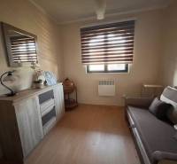 Rodinný  dom na predaj v Gabčíkove - Izba s pohovkou, skrinkou, dekoráciami a oknom s rolety, vhodná pre útulný rodinný dom.