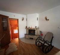 Rodinný  dom na predaj v Gabčíkove - Obývačka so smotanovými stenami a krbom, doplnená o kolísku a drevený nábytok. Rodinný dom.