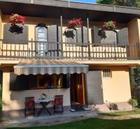 Rodinný  dom na predaj v Gabčíkove - Rodinný dom v Gabčíkove s balkónom, kvetmi, altánkom a dvoma stoličkami na trávniku.