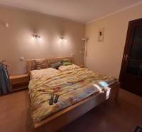 Rodinný  dom na predaj v Gabčíkove - Spálňa s manželskou posteľou, lampami a dreveným nábytkom v rodinnom dome.