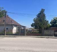 Rodinný dom na úžasnom pozemku. - Rodinný dom v Kráľovičových Kračanoch s oploteným pozemkom, stromami a zaparkovaným autom.