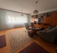 ☎️ 0918 846 340       Výrazne znížená cena len 210 000 eu. Dvojgenerač - Obývačka v rodinnom dome s knižnicou, pohovkou a kobercami na podlahe s dreveným dekorom.