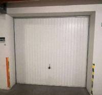 Garáž na prenájom. - Garáž v interiéri s bielymi dverami a bezpečnostnými značkami.