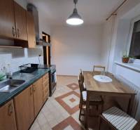 ☎️   0918 846 340           Byt v centre mesta na Jesenského ulici. - Kuchyňa v 1-izbovom byte so štvorcovými dlaždicami a dreveným dekorom na nábytku.