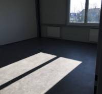 Kancelárský priestor 37,5 m2 na prenájom oproti OD TESCO v Dunajskej S - Prázdna kancelária na ulici Hlavná so svetlom cez okno a radiátormi pod oknom.