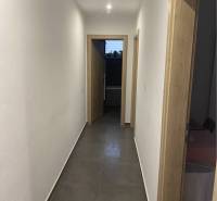 Na predaj: 3-izbový rodinný dom na predaj v obci Lesné Kračany - Úzka chodba rodinného domu s bielymi stenami a dlažbou, osvetlená bodovým svetlom.