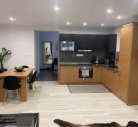 Na predaj: 3-izbový rodinný dom na predaj v obci Lesné Kračany - Kuchyňa v rodinnom dome s čiernou a drevenou kuchynskou linkou a pohovkou.