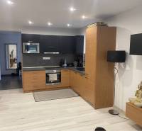 Na predaj: 3-izbový rodinný dom na predaj v obci Lesné Kračany - Kuchyňa v rodinnom dome s drevenými skrinkami a podlahou s dreveným dekorom.