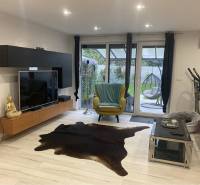 Na predaj: 3-izbový rodinný dom na predaj v obci Lesné Kračany - Obývacia izba v rodinnom dome s televízorom, dekorom Buddhu a terasovým výhľadom.