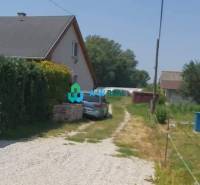 Krásny veľký pozemok v tichej časti obce Ňárad - Vidno dom a auto na ulici, okolo sú Pozemky - bývanie.