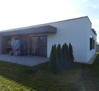4. ETAPA!!! MODERNÁ NOVOSTAVBA - 3 izbový nízkoenergetický bungalov vy - Rodinný dom s terasou a záhradou má jednoduchú architektúru a zelený trávnik.