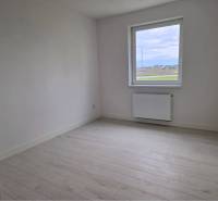 NOVOSTAVBA! Krásny, moderný a priestranný 3-izbový byt s veľkou logiou - Svetlá izba s podlahou s dreveným dekorom v 3-izbovom byte, oknom s výhľadom.