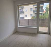 NOVOSTAVBA! Krásny, moderný a priestranný 3-izbový byt s veľkou logiou - Izba v 3-izbovom byte s podlahou s dreveným dekorom a balkónom.