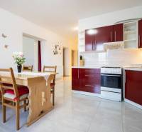 Dvojpodlažný rodinný dom s veľkým pozemkom na predaj v obci Jahodná - Kuchyňa v rodinnom dome s červenými skrinkami, dreveným stolom a dekoráciami na stene.