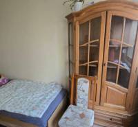 Na prenájom 3-izbový zariadený byt - Dunajská Streda - Izba v 3-izbovom byte s posteľou, skriňou a stoličkou, podlaha s dreveným dekorom.