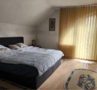 EXKLUZÍVNE LEN U NÁS! - Veľký rodinný dom - Dunajská Streda - Spálňa v rodinnom dome s posteľou, jemnými závesmi a podlahou s dreveným dekorom.