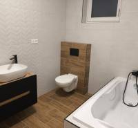 Rezervované / 4-izbový rodinný dom v obci Michal na Ostrove - Kúpeľňa v rodinnom dome s vaňou, umývadlom, toaletou a podlahou s dreveným dekorom.