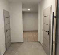 Rezervované / 4-izbový rodinný dom v obci Michal na Ostrove - Chodba v rodinnom dome s dverami a podlahou s dreveným dekorom.