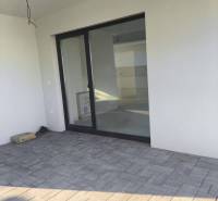 4 izbový rodinný  dom v obci Michal na Ostrove! - Terasa rodinného domu v Michale na Ostrove s veľkými presklenými dverami a dlažbou.