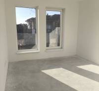 4 izbový rodinný  dom v obci Michal na Ostrove! - Prázdna miestnosť s veľkými oknami, bielymi stenami, betónovou podlahou v rodinnom dome.